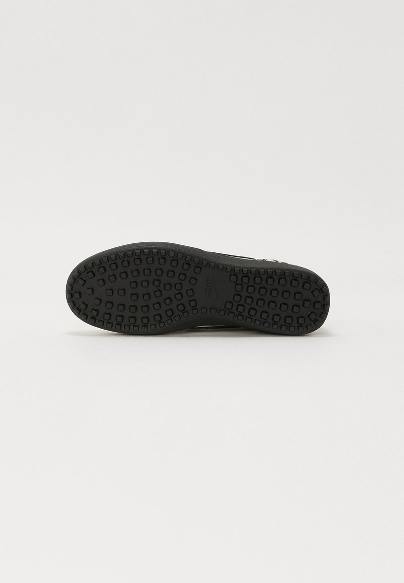 Semelle de sneaker noire avec une surface en caoutchouc texturé, comportant des motifs rectangulaires et carrés pour une adhérence et une durabilité accrues.