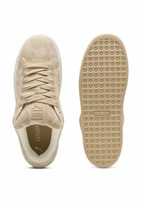 Beige színű velúr tornacipők texturált gumitalppal, lapos fűzőkkel és párnázott bokarészel. Diszkrét logó található a nyelvén és az oldalán.