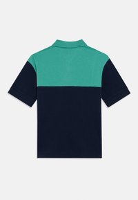 Μπλουζάκι πόλο με διχρωμία, με πράσινο επάνω μέρος και σκούρο μπλε κάτω μέρος. Κοντά μανίκια και κλασικό γιακά. Κατασκευασμένο από βαμβάκι.