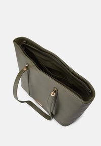 Olīvu zaļš teksturēts iepirkumu soma ar divām rokturiem, zelta krāsas detaļām un rāvējslēdzēja aizdari. Iekšpusē ir papildu kabatas organizācijai.