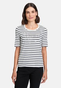 Striped t-shirt in white and navy, featuring short sleeves, a round neckline, and a decorative design in the center made of small beads.