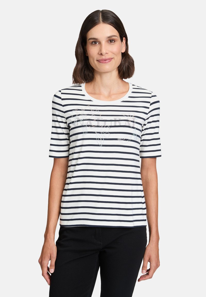 Striped t-shirt in white and navy, featuring short sleeves, a round neckline, and a decorative design in the center made of small beads.