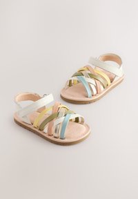 Sandały na paski z wieloma kolorowymi paskami w biały, różowy, zielony, złoty i niebieski, z beżową wyściółką i brązową podeszwą.