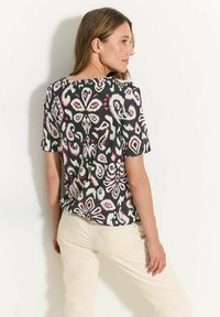 Top de manga corta negro con un colorido patrón floral y de paisley en rosa y blanco. Fabricado en un tejido ligero y texturizado.