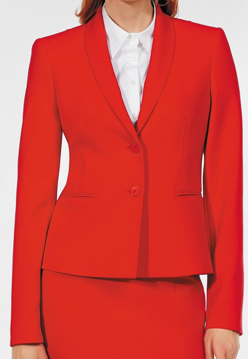 Blazer rouge sur mesure avec un revers cranté, fermeture à un bouton et deux poches frontales. Fabriqué en tissu lisse avec des détails de couture minimaux.