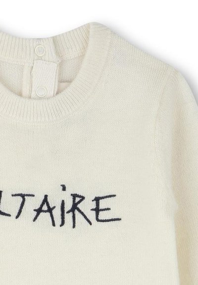 Crème-kleurige trui met een ronde halslijn, voorzien van een gestructureerd breiwerk en donkerblauwe geborduurde tekst met de tekst "VOLTAIRE." Twee knopen aan de achterkant.