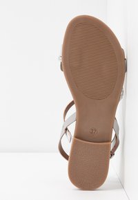 Semelle de sandale avec talon et avant-pied marron texturé, taille 37 indiquée, avec des sangles blanches partiellement visibles sur fond blanc.