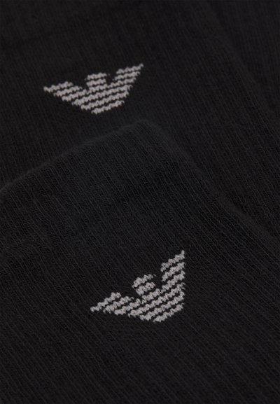 Chaussettes noires en tissu doux avec une texture côtelée ; arborent un logo blanc avec un motif géométrique et des lignes angulaires.