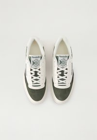 Green and white sneakers with suede and leather materials, perforated toe, flat laces, and a logo on the tongue and side.