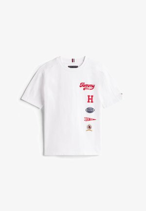 Hvid bomulds-T-shirt med røde broderede logoer, herunder "Tommy", et stort "H" og forskellige patches, med rund halsudskæring og korte ærmer.