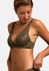 Bralette en dentelle vert olive avec larges bretelles, motif floral sur les bords des bonnets, tissu lisse, forme triangulaire, fini avec une bande élastique douce.