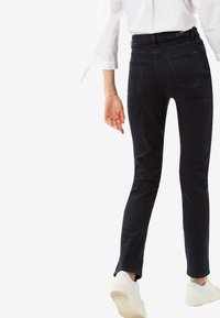 Mustat denim-farkut, joissa on kapea istuvuus, keskikorkea vyötärö ja kaksi takataskua. Yhdistettyinä valkoisiin tennareihin ja reilusti istuvaan valkoiseen paitaan.