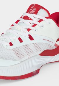 Chaussure de sport blanche et rouge avec des lacets blancs, une tige en mesh et le texte "SKY: NEXUS 01" sur le côté près de la semelle intermédiaire.