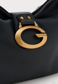 Schwarze Lederhandtasche mit einer strukturierten Oberfläche, goldfarbener runder Hardware mit einem 'G'-Motiv und einem sicheren oberen Verschluss.