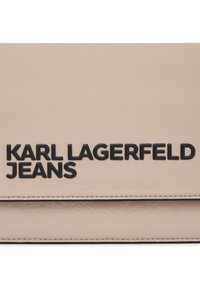Borsa a mano in pelle sintetica beige con logo impresso nero "KARL LAGERFELD JEANS", texture liscia e dettagli cuciti.