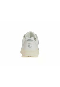 Chaussure de sport blanche avec une tige en mesh, des accents lisses et une semelle texturée. Logo argenté à l'arrière. Design minimaliste.