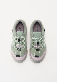 Chaussures de randonnée vert clair avec un dessus texturé, un système de laçage bungee et des accents gris. Embout renforcé et semelle intérieure rembourrée.