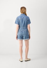 Denim jumpsuit med korte ermer og mansjetter, lyseblå farge, slank midje, to baklommer og krage, med beltedesign.