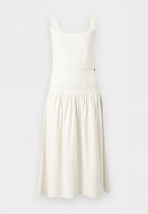 Λευκό μίντι φόρεμα χωρίς μανίκια με τετράγωνο ντεκολτέ, εφαρμοστό μπούστο και φούστα με πιέτες σε μονόχρωμο φόντο.