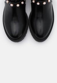 Czarne skórzane botki do kostki z zaokrąglonym noskiem, z złotymi i perłowymi ozdobami wzdłuż górnej krawędzi oraz teksturowaną gumową podeszwą.