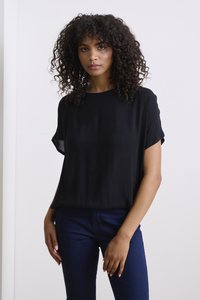 Black ribbed short-sleeve top with a relaxed fit, paired with dark blue fitted jeans. Smooth texture, round neckline, and subtle drape.