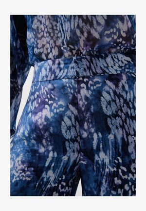 Blaues und lila gemustertes Stoff mit einer glatten Textur, das abstrakte Formen und einen taillierten Bund aufweist. Nahaufnahme der Kleidungsdetails.