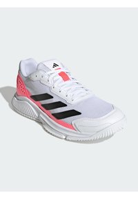 Chaussure de sport blanche avec des rayures noires et des accents roses, dotée d'une semelle texturée et de lacets, présentée en vue à trois quarts.