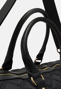 Borsa a tracolla nera trapuntata con manici in pelle, zip dorata e dettagli in oro. Texture morbida con un design strutturato. Include una tracolla regolabile.