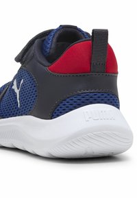 Chaussure de sport bleu marine avec des panneaux en mesh, accents gris, talon rouge et semelle blanche. Dotée d'une sangle réglable et de détails avec logo sur le côté.