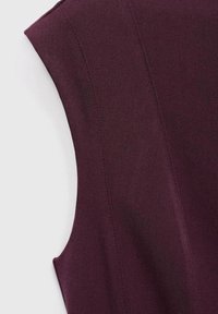 Maroon majica bez rukava od teksturiranog materijala, s čistim linijama i suptilnim šavovima. Dizajn je jednostavan, bez vidljivih uzoraka ili metalnih dijelova.