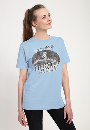 Kvinde med brunt hår i en hestehale bærer en lyseblå T-shirt med Betty Boop og teksten "Red Hot Mamma" i vintage tegneseriestil.