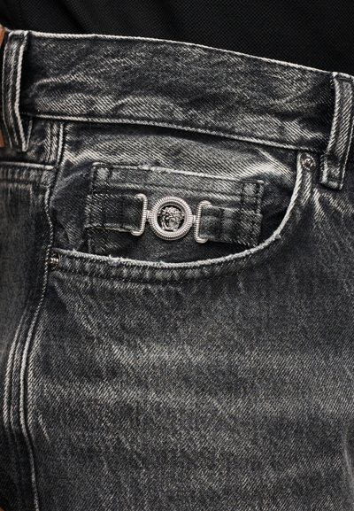 Juodi džinsai iš džinsinio audinio su dėvėtu tekstūros efektu, sidabro spalvos mygtuku su liūto emblemą ir galinės kišenės dizainu.