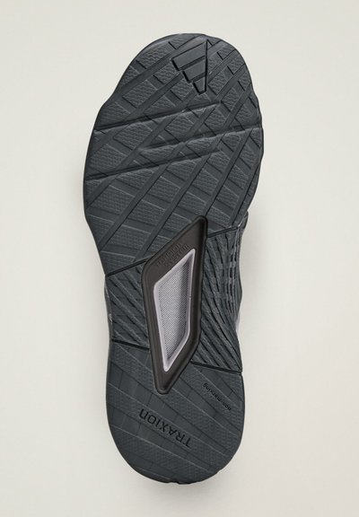 Black athletic shoe sole with textured traction pattern. Features a recognizable torsion system component in gray with mesh detailing.