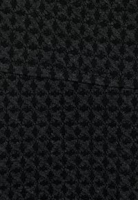 Tejido negro texturizado con un patrón geométrico repetido, material de punto suave y una superficie ligeramente elevada.