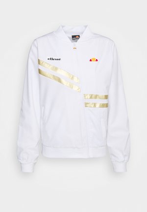 Chaqueta blanca con cremallera y rayas doradas, y logo negro. Cuenta con un cuello alzado y puños elásticos. Textura de tela suave.