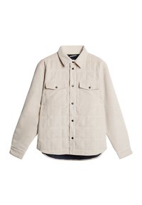 Beige kordskjorta med knäppning framtill, två bröstfickor och långa ärmar. Har en lätt rundad nederkant och ett texturerat tyg.