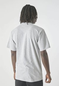 Graues Baumwoll-T-Shirt mit kurzen Ärmeln, lockerer Passform, rundem Halsausschnitt, mit einer subtilen Textur und einem kleinen Etikett auf der Rückseite.