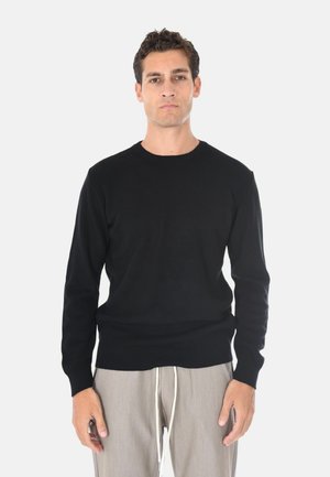 Maglione nero a coste con scollo rotondo, realizzato in un morbido materiale a maglia. Presenta maniche lunghe e una silhouette aderente.