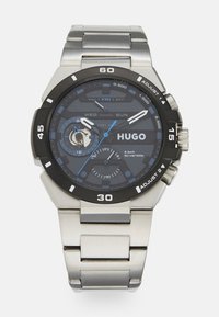 Metall-Armbanduhr mit einem blauen und schwarzen Zifferblatt. Zu den Funktionen gehören eine Datums- und Wochentagsanzeige, silberne Akzente und ein Armband aus Edelstahl. Wasserdicht bis 50 m.