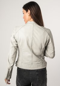 Giacca da moto in pelle grigia chiara con design aderente, dettagli trapuntati sulle spalle e polsini con zip, mostrata da dietro.