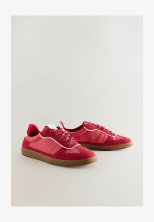 Punased tossud, millel on erinevad siledate ja tekstureeritud materjalide kombinatsioon. Omadusteks on paelad, valged detailid ja helepruun kummitald.