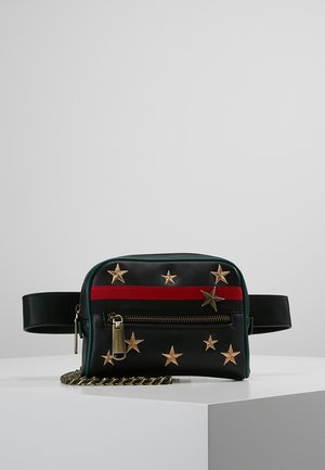 Schwarze Ledergürteltasche mit goldenen Sternverzierungen, einem horizontalen roten Streifen, Frontreißverschlusstasche und einem Metallketten-Detail auf weißem Untergrund.