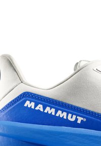 Blaue und graue Schuhe aus strukturiertem Stoff mit einem auffälligen weißen Logo. Die Nähte sind entlang der Kanten sichtbar.