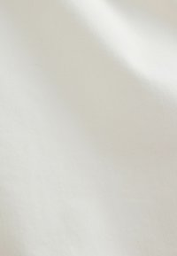 Tissu blanc avec des plis doux et une surface lisse légèrement texturée.
