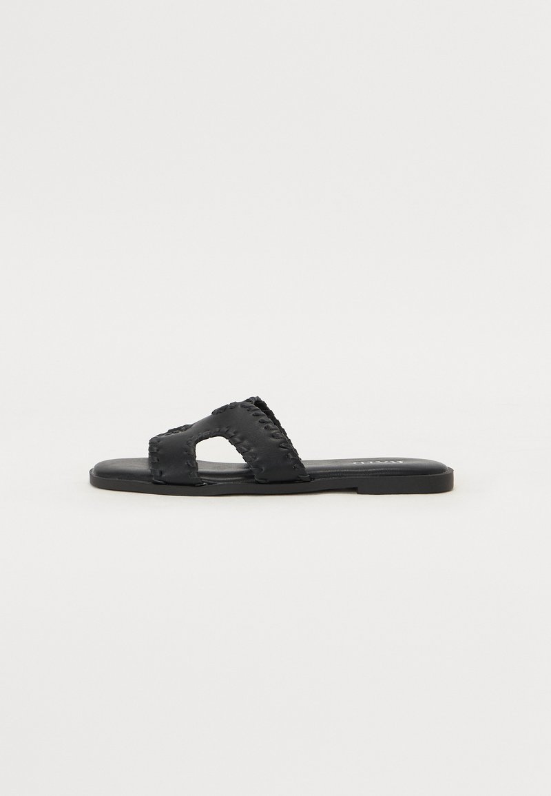 Black flat sandals with a wide double band and cut-out design, featuring stitched detailing along the edges and a smooth sole.