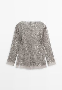 Top in paillettes argento con maniche lunghe, scollo quadrato e orlo trasparente. Il tessuto è completamente ricoperto di paillettes riflettenti.