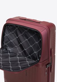 Valigia rigida bordeaux con texture a righe, chiusura con zip e un interno nero caratterizzato da una fodera con logo.
