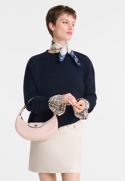 Navy knit sweater, cream skirt with front buttons, checkered shirt cuffs, pale pink handbag with a curved shape and matching closure.