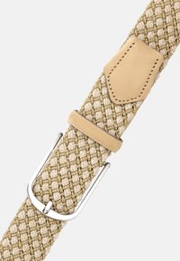 Beige vävd tygbälte med silverfärgad metallspänne och bruna läderdetaljer på en ljus bakgrund.