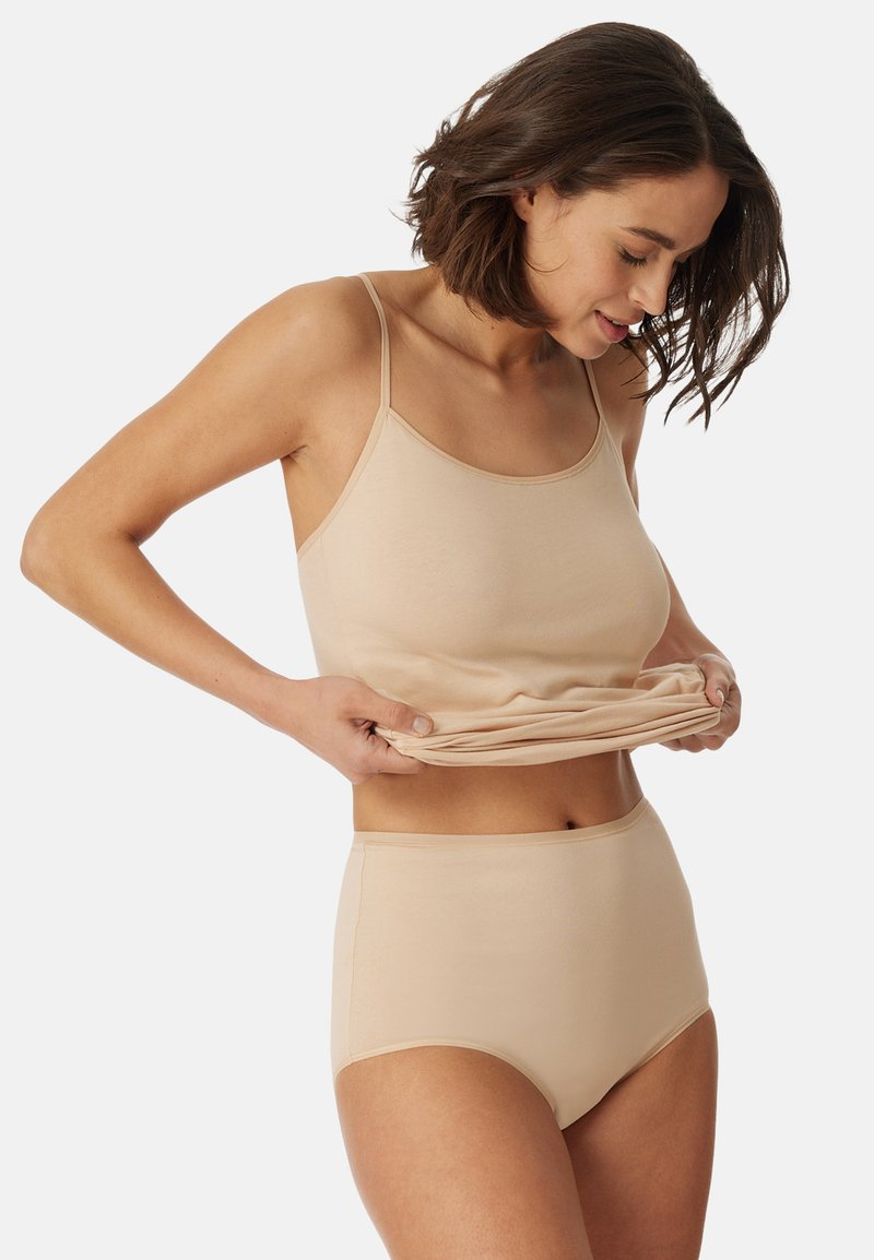 Beige tank top ja korkeat vyötäröiset alushousut, jotka on valmistettu sileästä, joustavasta kankaasta. Tankissa on ohutolkaimet ja pyöreä kaula-aukko.